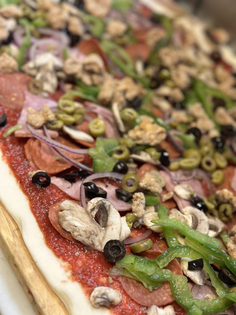 Close view of a deluxe pizza topped with pepperoni, green peppers, black olives, onions and mushrooms