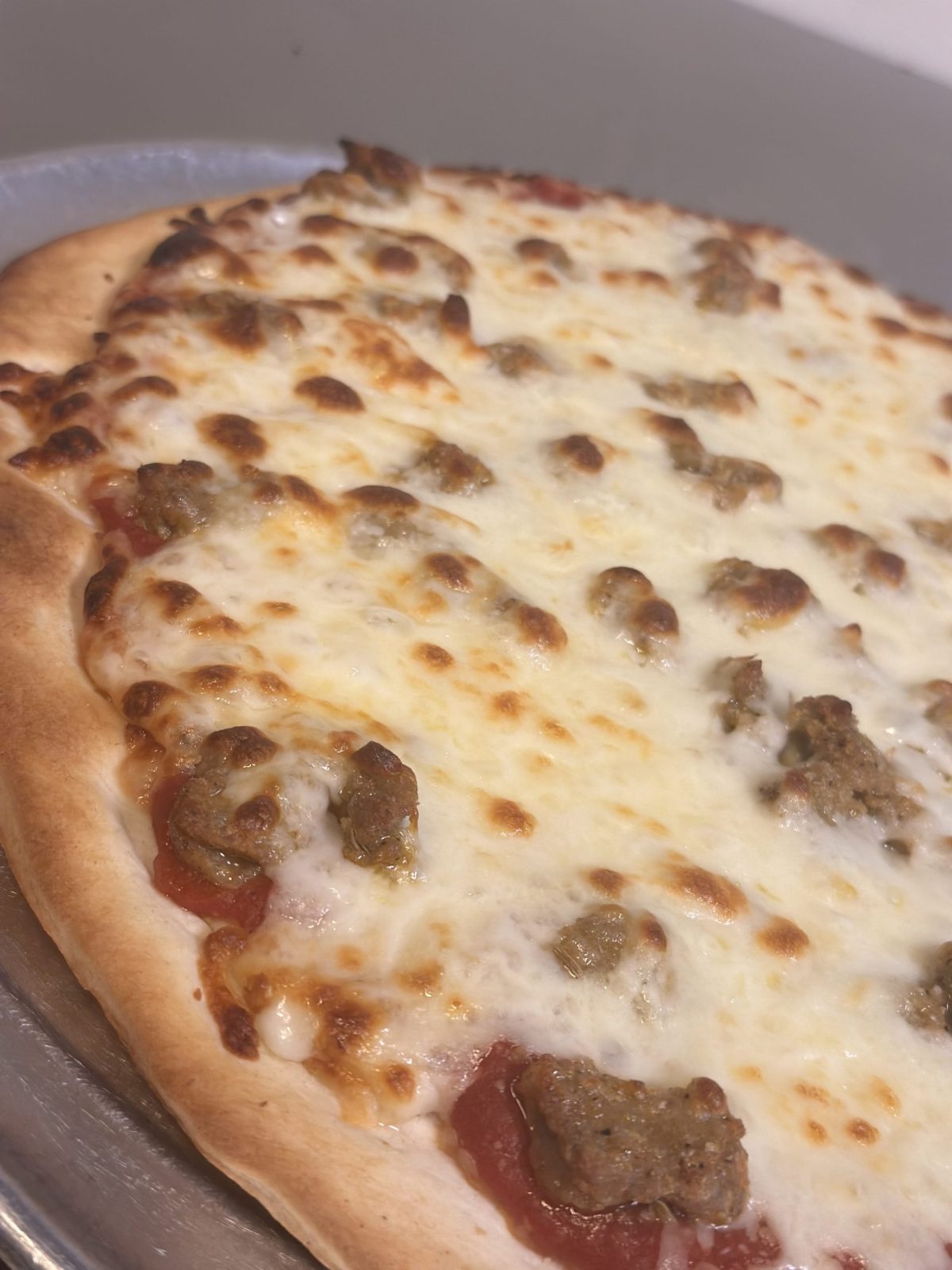A hand-tossed sausage pizza with browned mozzarella